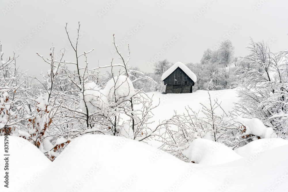 雪山木屋的极简主义冬季景观。多云，景观照片