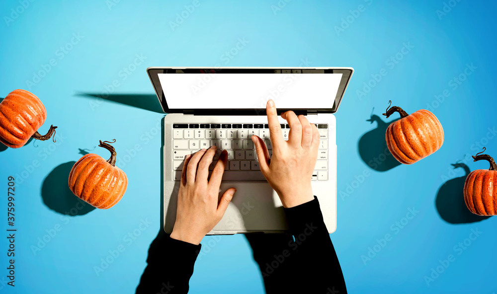 Autumn pumpkins with person using a laptop computer from above