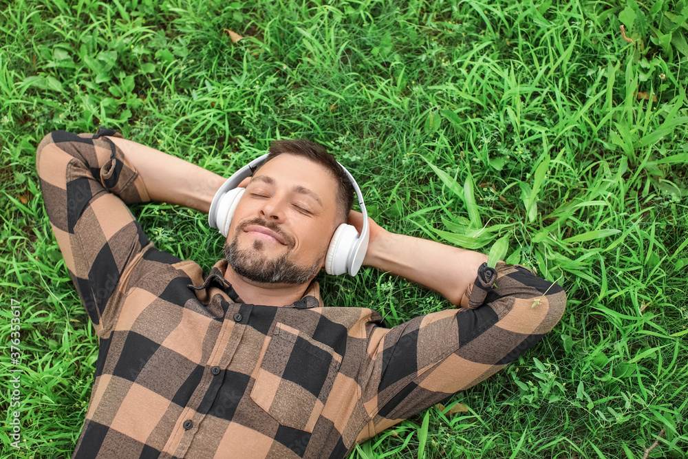 Handsome man listening to music while relaxing in park