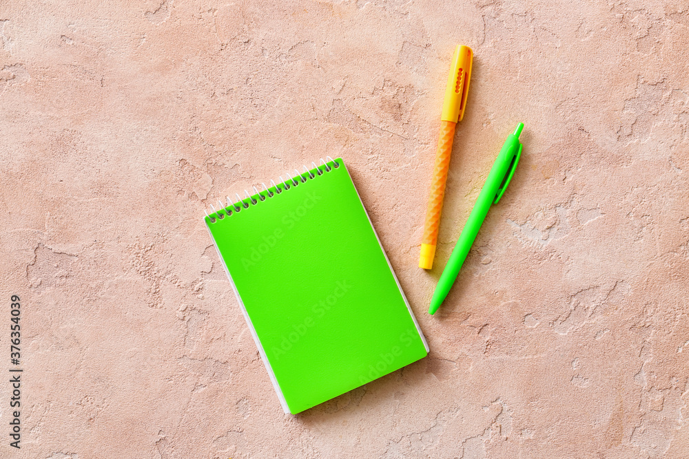 Notebook and pens on color background