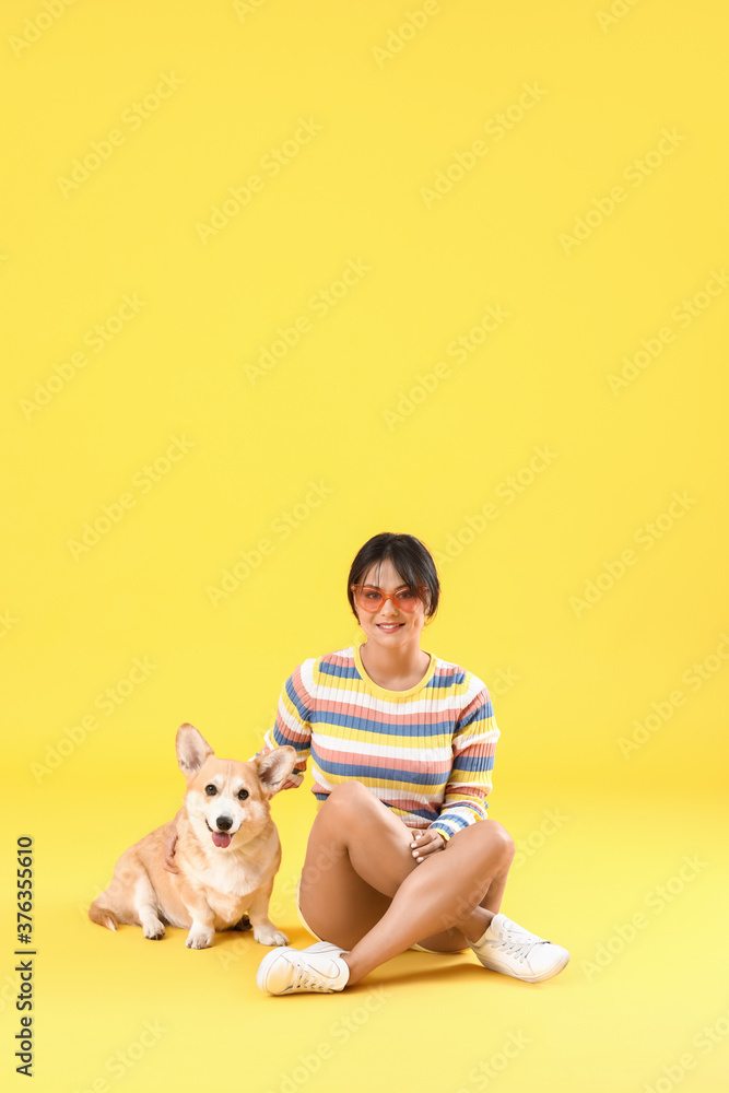 Woman with cute corgi dog on color background