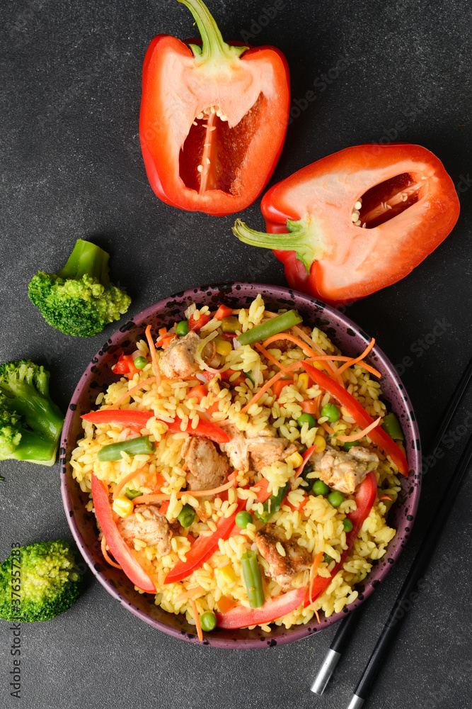 Bowl with tasty fried rice on dark background