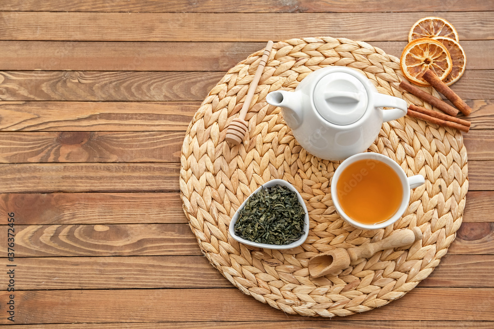 Cup of tea with dry leaves and teapot on table