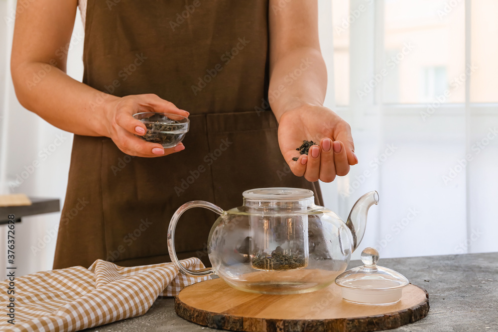 女人在家里用壶泡绿茶