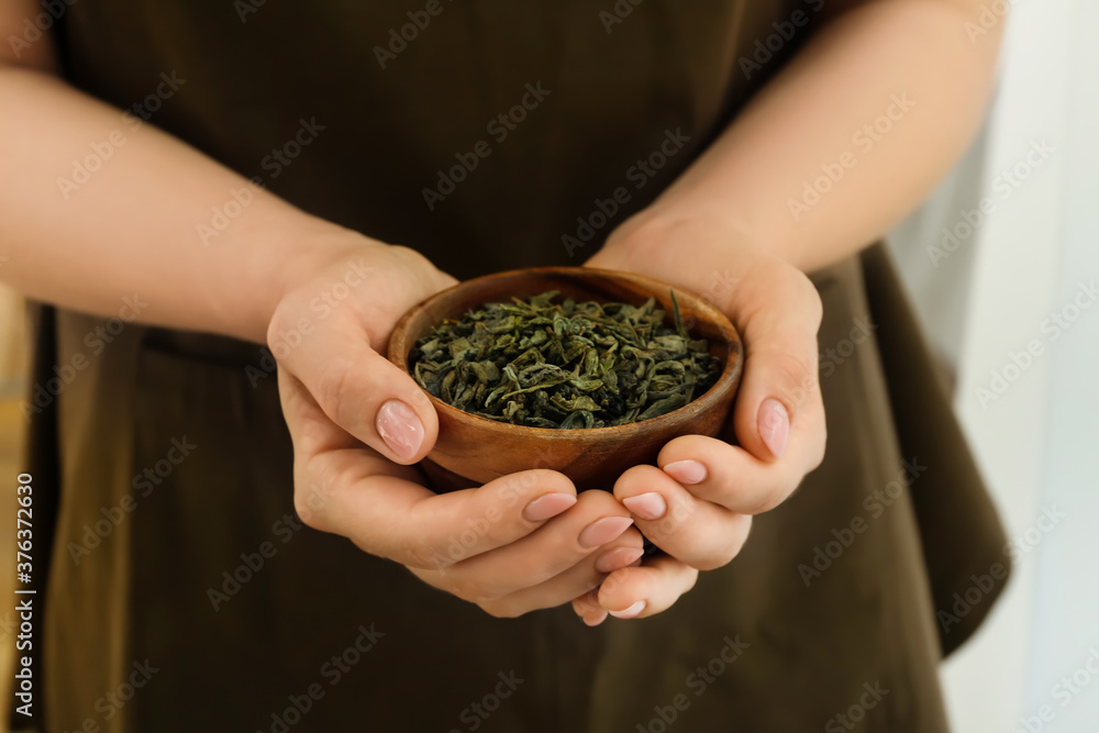 Woman with dry tea leaves in bowl, closeup