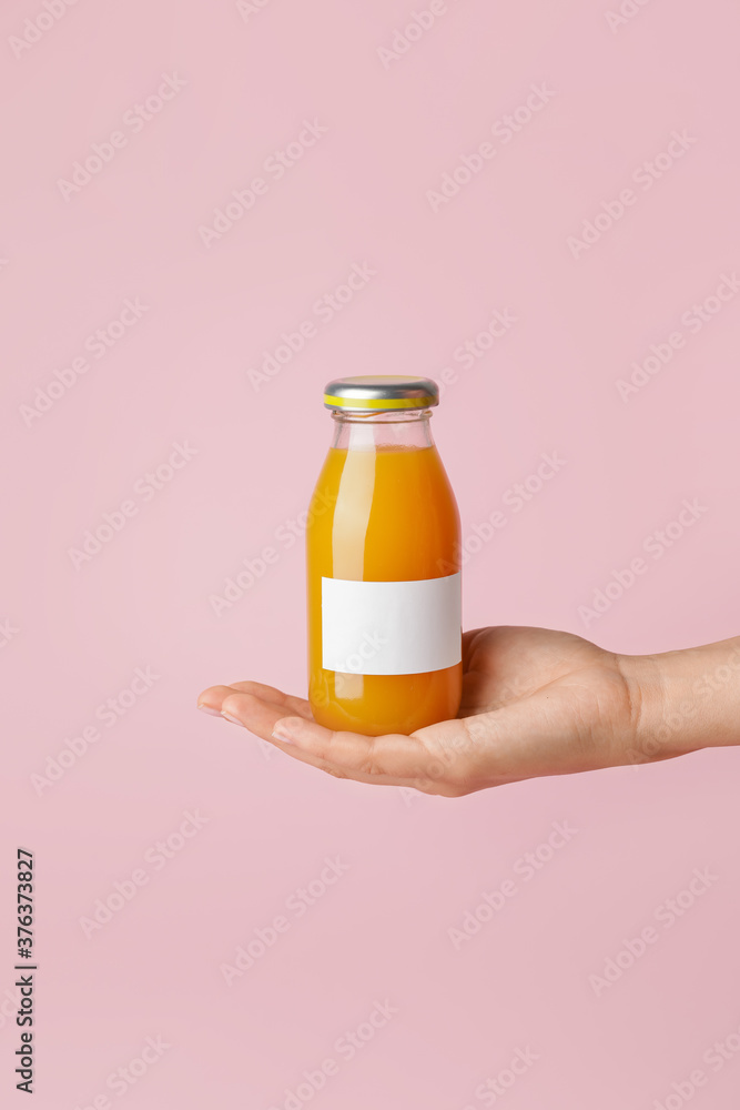 Female hand with bottle of juice on color background