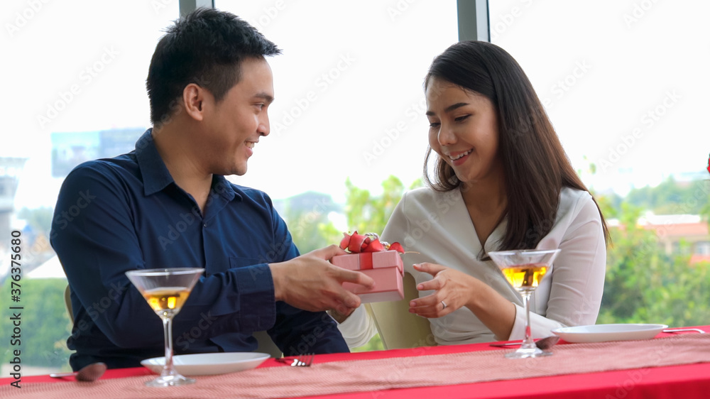 Romantic couple giving gift to lover at restaurant . Happy couple lifestyle .