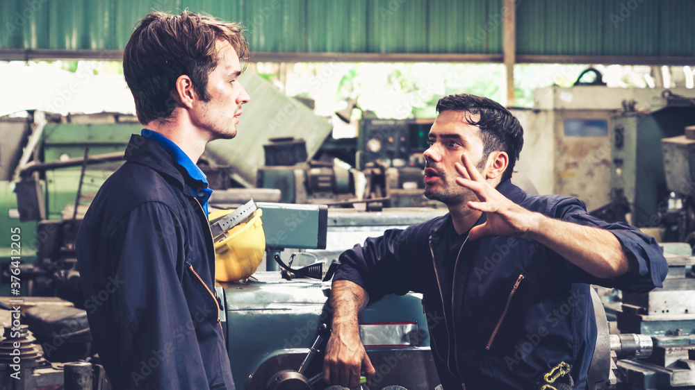 Tired factory workers taking a break and talking to coworker in the factory . Industry and engineeri