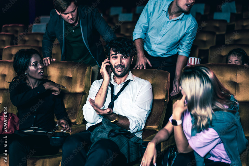 Annoying man talking on the mobile phone at the movie theater people in cinema is angry him