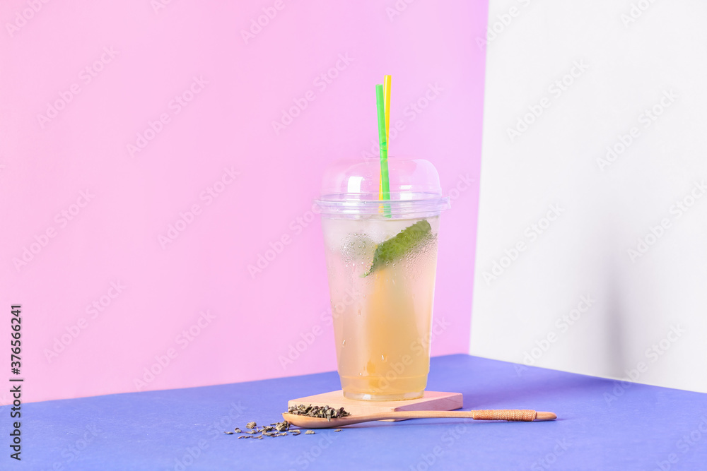 Cup of tasty cold ice tea on color background