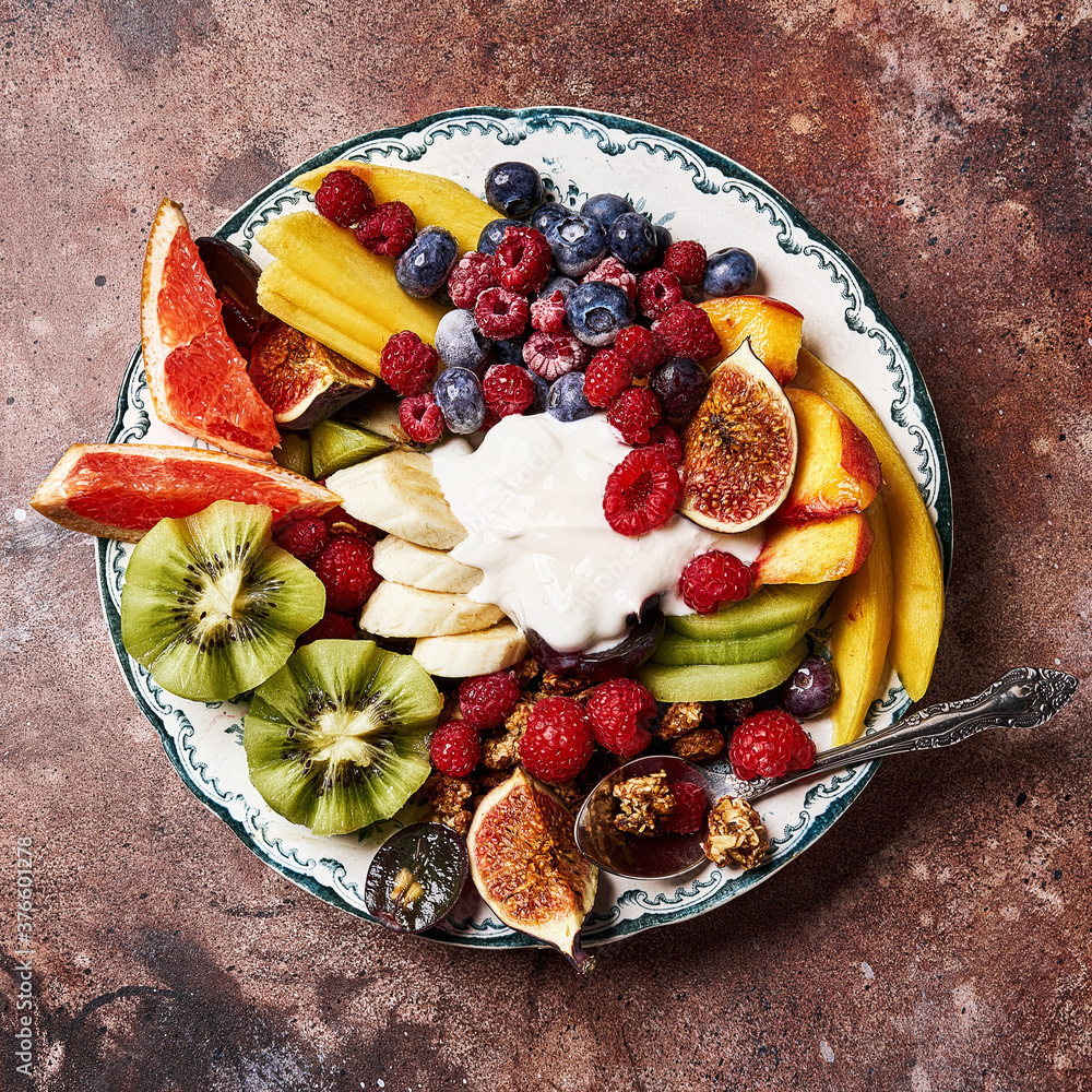 Assorted sliced fruits on vintage plate. Mango, kiwi fruits, figs, grape, bananas, raspberries and b