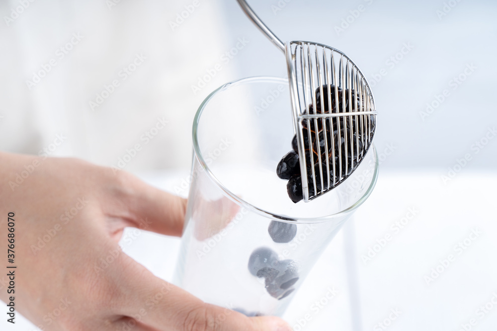 Making bubble tea, scoop and pour cooked brown sugar flavor tapioca pearl bubble balls into cup on w