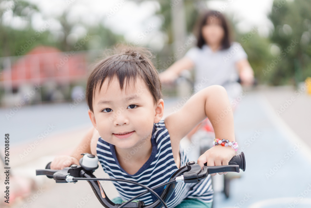 3岁快乐的蹒跚学步的亚洲男孩在家乡村庄的街道上骑自行车。男孩骑自行车去p