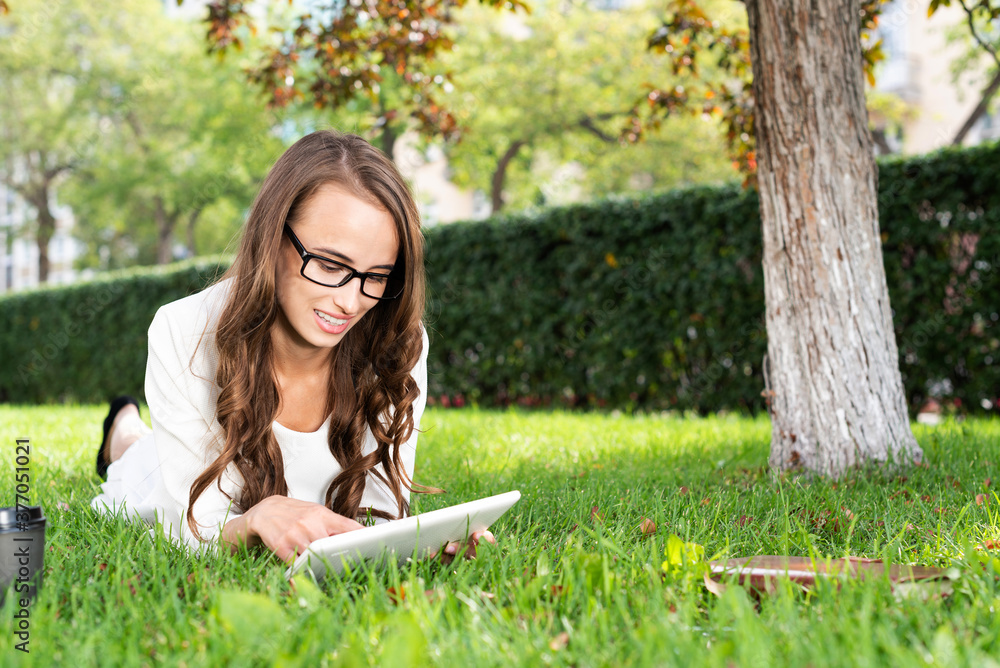 Young woman with digital tablet laying on grass