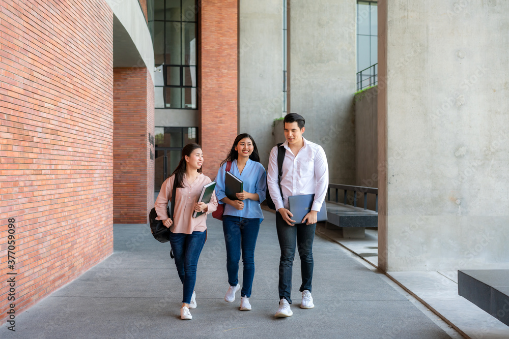 大学课间休息时，三名亚裔学生在大学礼堂一起散步和交谈。