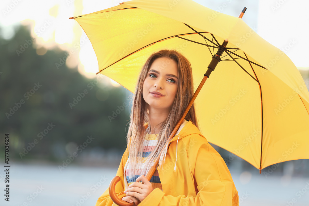 美丽的年轻女子，带着雨伞，在户外穿着雨衣