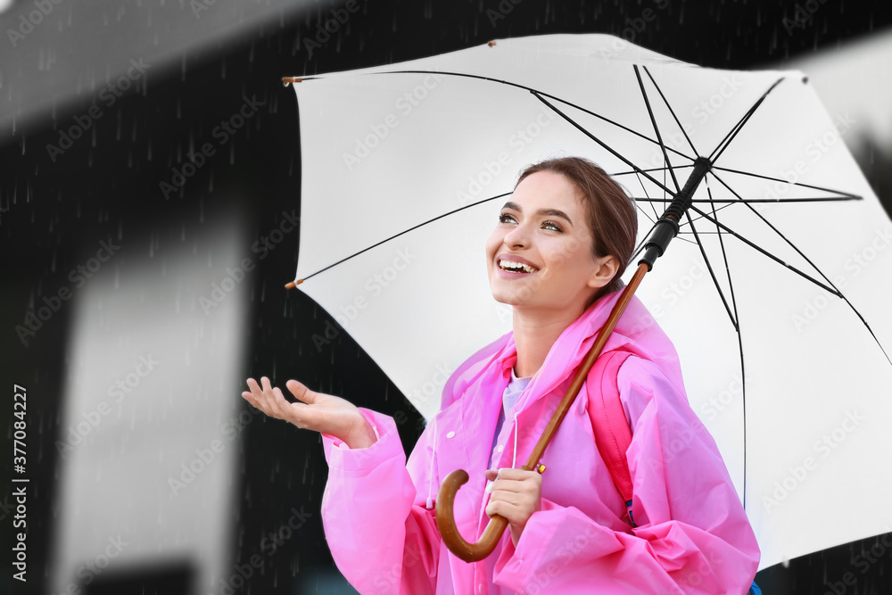 美丽的年轻女子，带着雨伞，在户外穿着雨衣