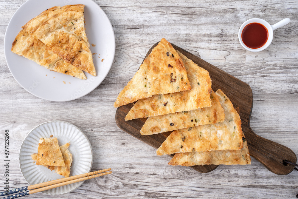 台湾美食——明亮的木桌背景上美味的葱花饼，传统