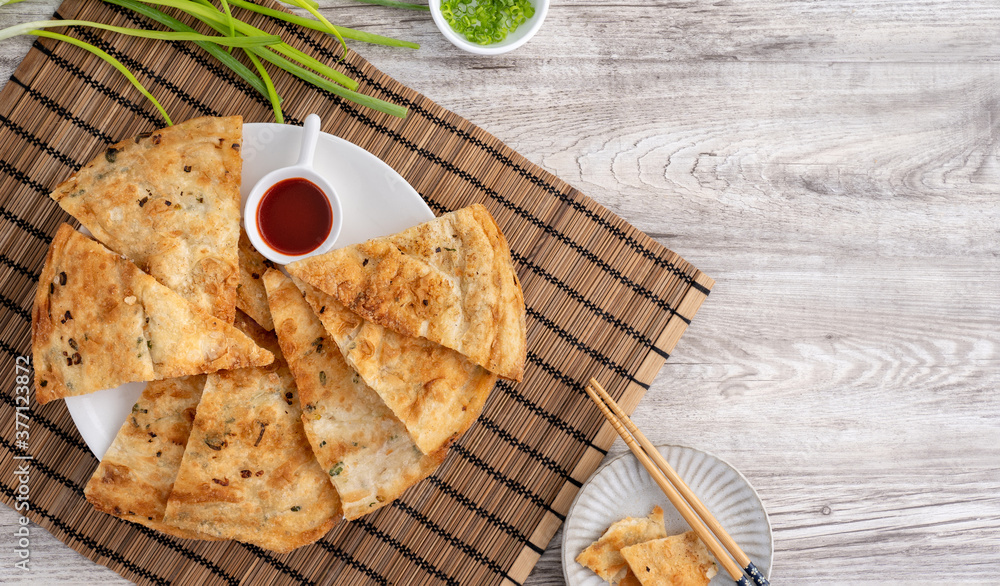 台湾美食-明亮的木桌背景上美味的葱花饼，传统