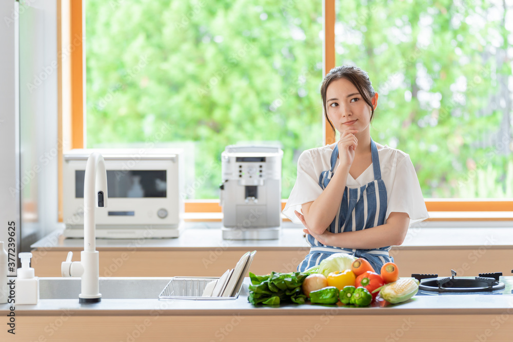 キッチンで考え事をする女性