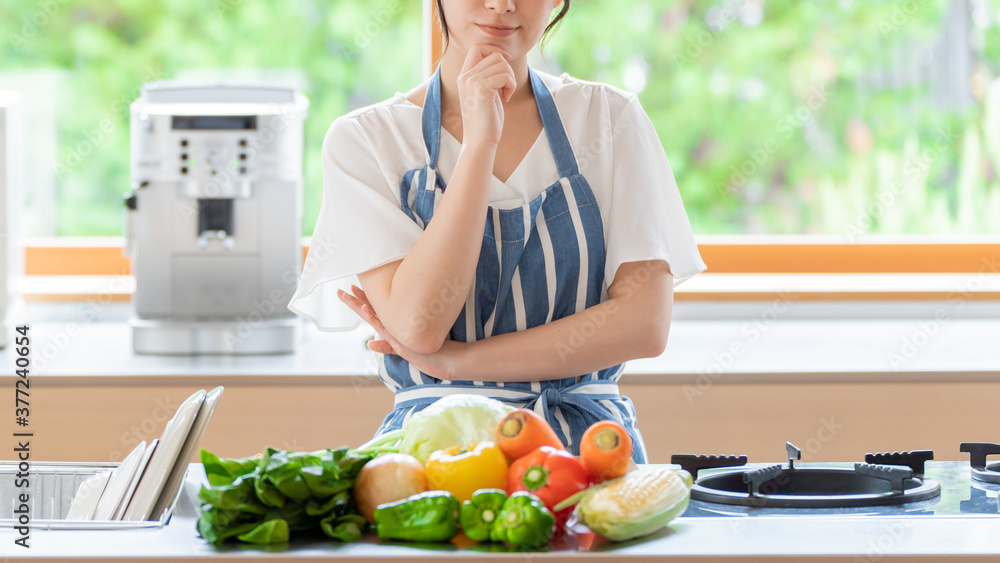 キッチンで考え事をする女性