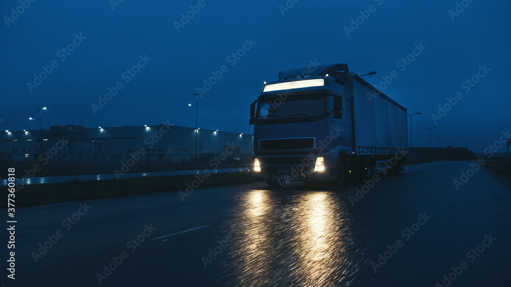 Blue Long Haul Semi-Truck with Cargo Trailer Full of Goods Travels At Night on the Freeway Road, Dri