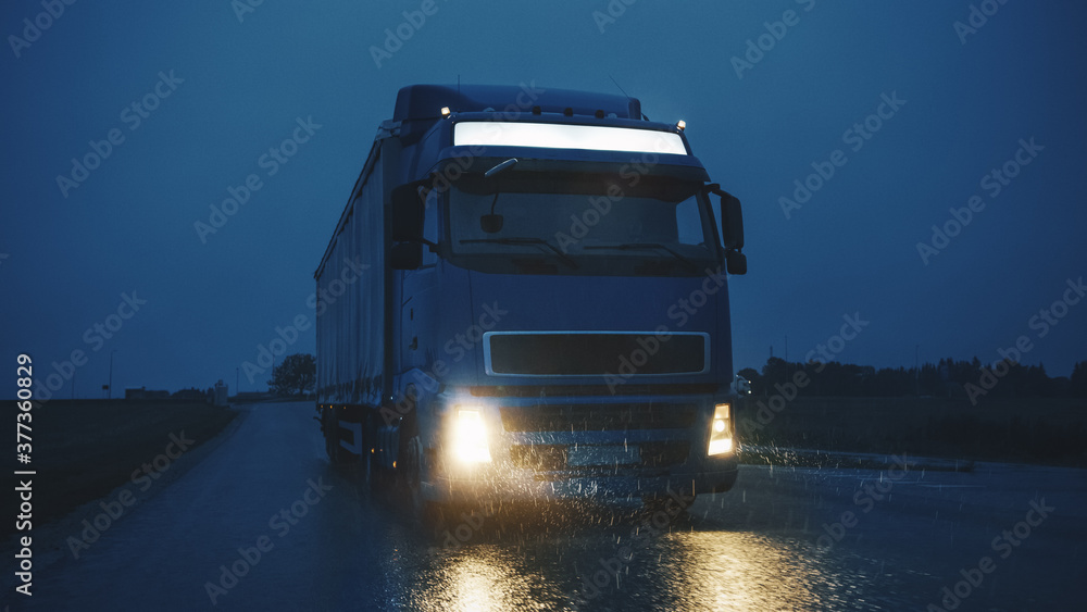 Blue Long Haul Semi-Truck with Cargo Trailer Full of Goods Travels At Night on the Freeway Road, Dri