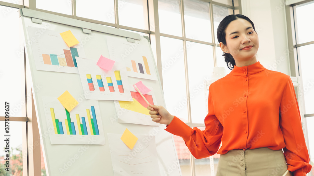 Young woman explains business data on white board in casual office room . The confident Asian busine