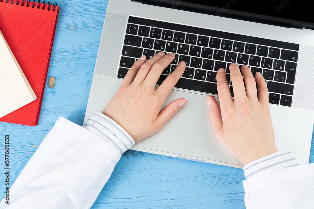 Top view of doctor hands typing at laptop