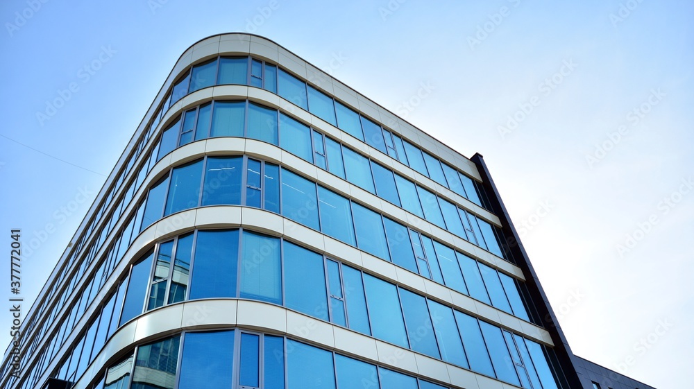 Blue curtain wall made of toned glass and steel constructions under blue sky. A fragment of a buildi