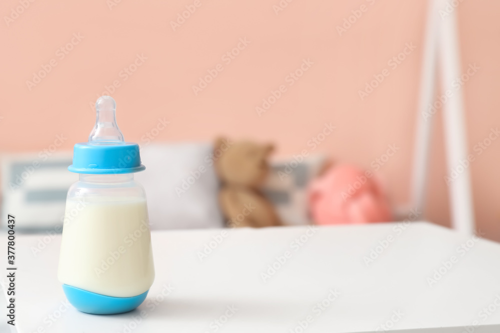 Bottle of milk for baby on table in room