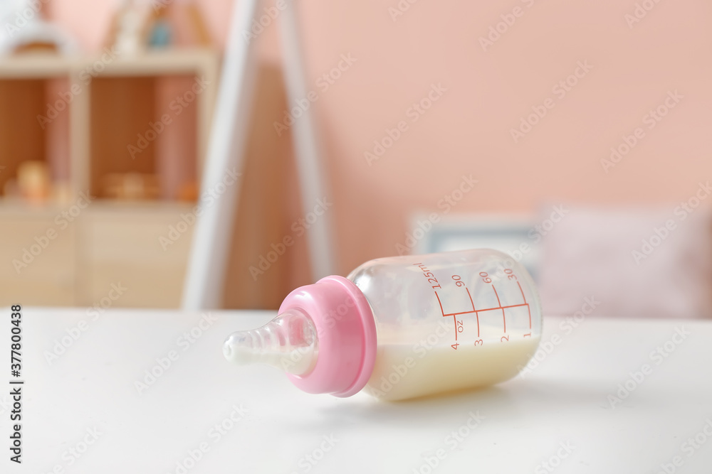 Bottle of milk for baby on table in room