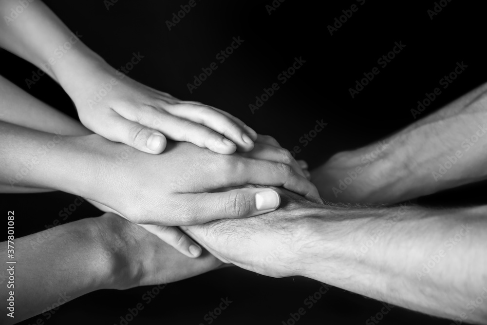 Hands of family on dark background