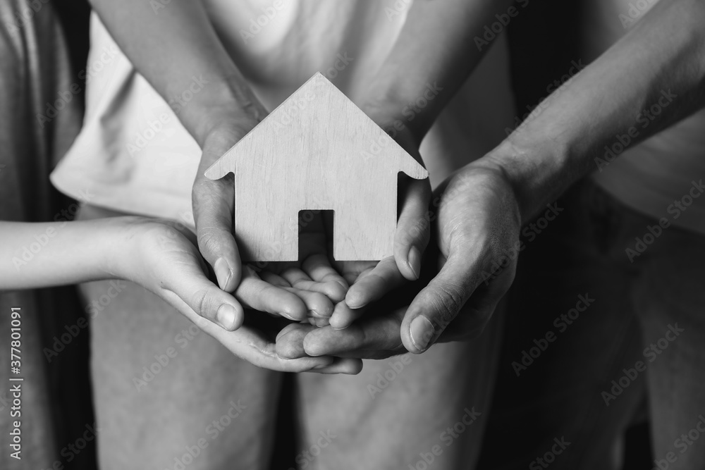 Hands of family with small house, closeup