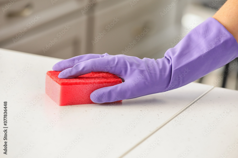 Woman in rubber gloves cleaning kitchen, closeup