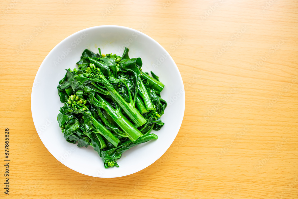 A dish of Chinese vegetable stir-fried Chinese kale and cabbage heart on a wooden table