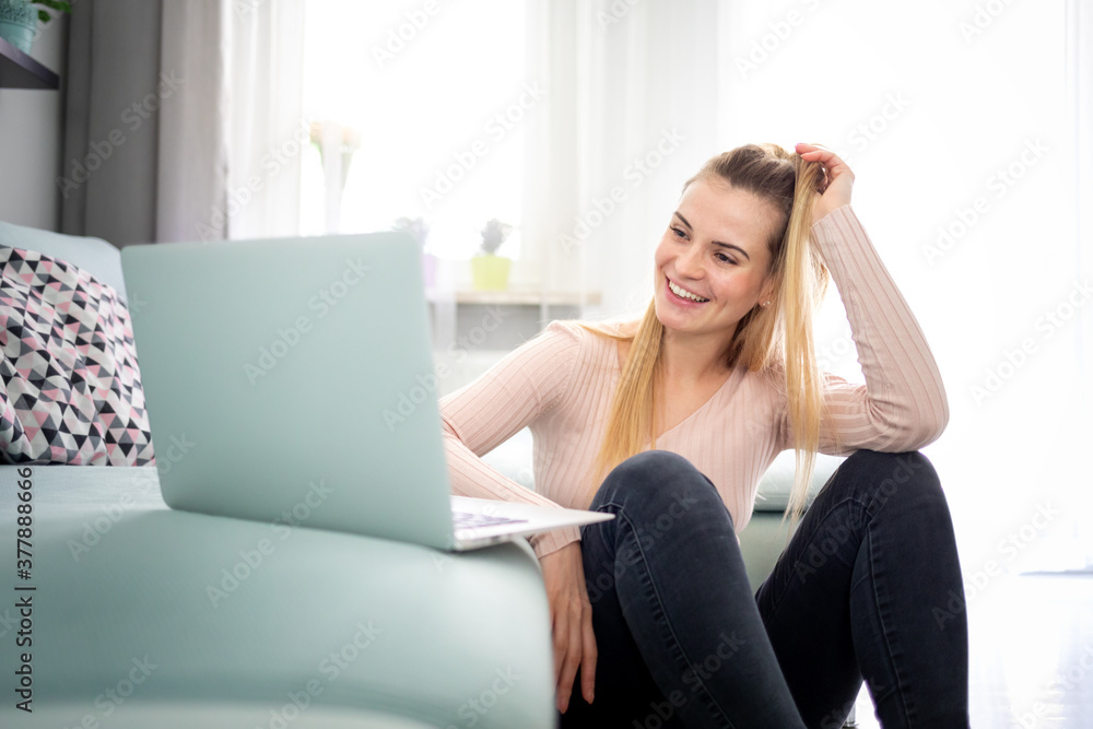 Relaxed woman enjoying time at home using laptop sitting near sofa