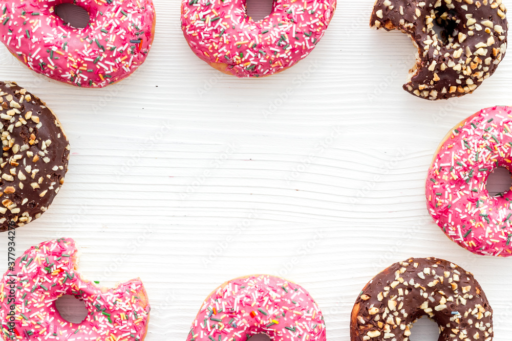 Frame of donuts with icing and sprinkles, overhead view. Colorful bakery