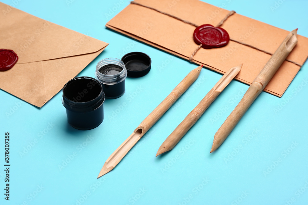 Supplies for calligraphy practice and envelopes on color background