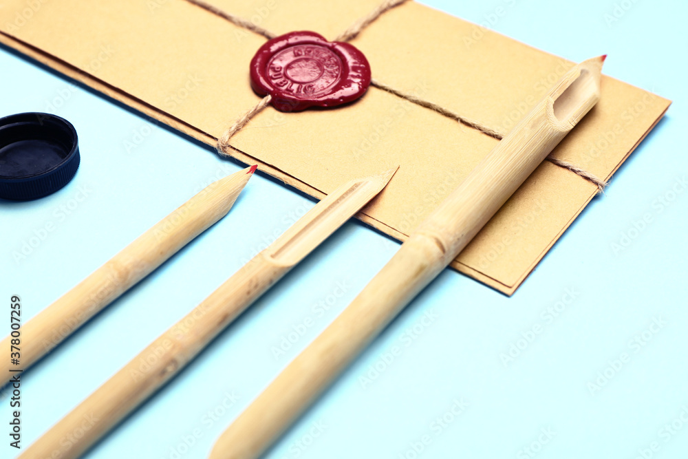 Supplies for calligraphy practice and envelopes on color background