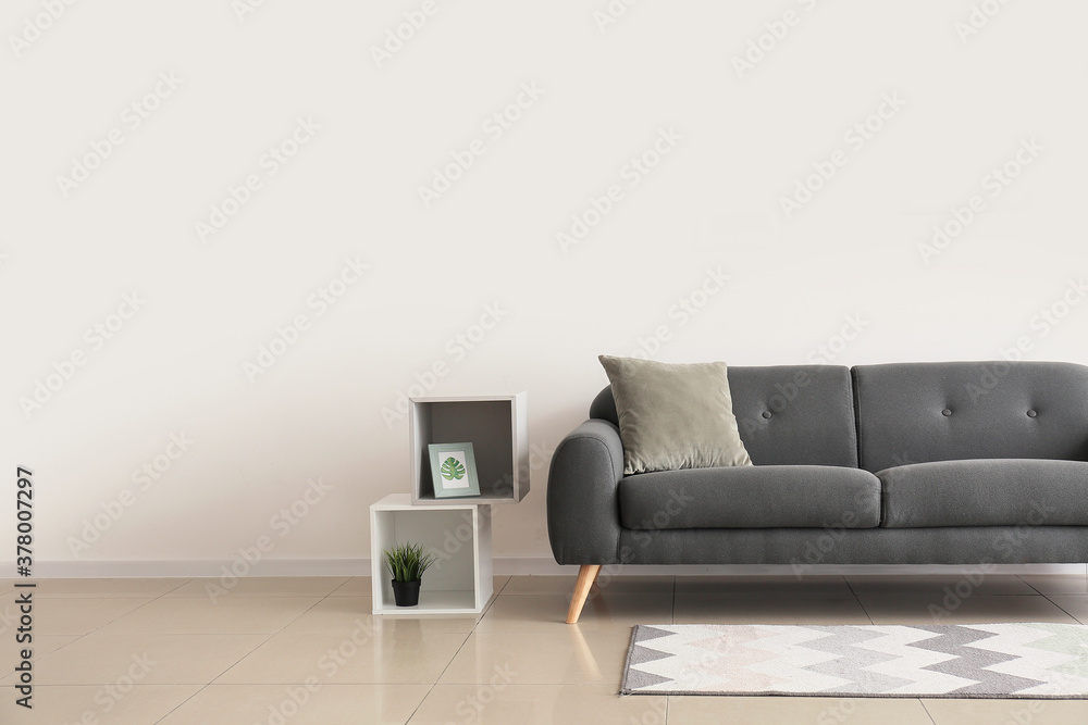 Comfortable sofa near white wall in room