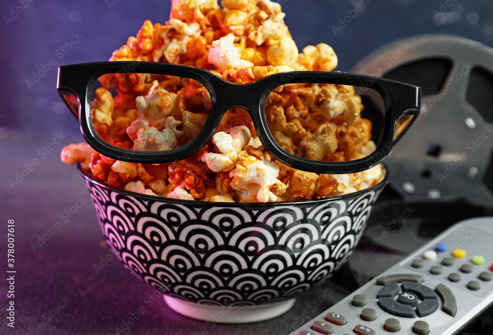 Popcorn, 3D glasses and remote control on dark background