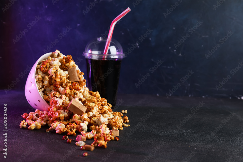 Sweet caramel popcorn with cola on dark background