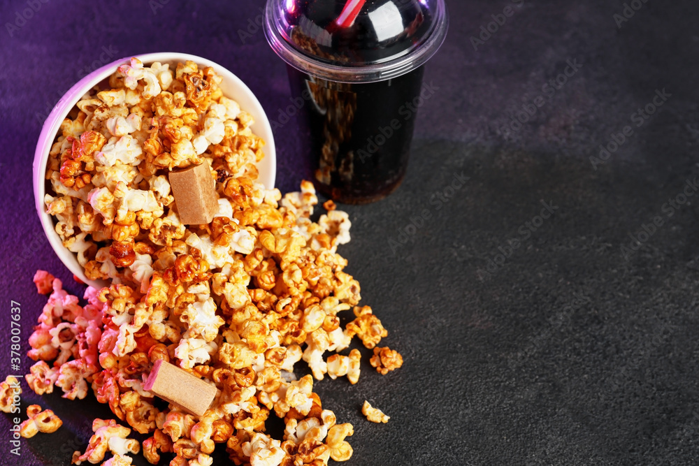 Sweet caramel popcorn with cola on dark background