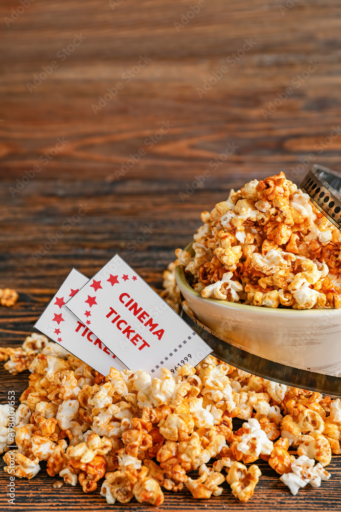 Bowl of tasty popcorn with cinema tickets on wooden background