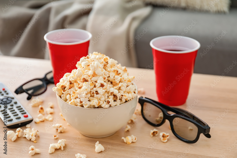 Popcorn, cola, 3D glasses and remote control on table in room