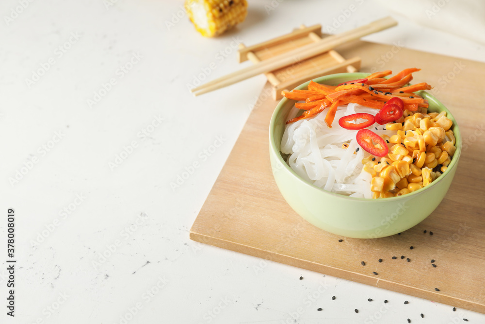 Bowl with tasty rice noodles and vegetables on table