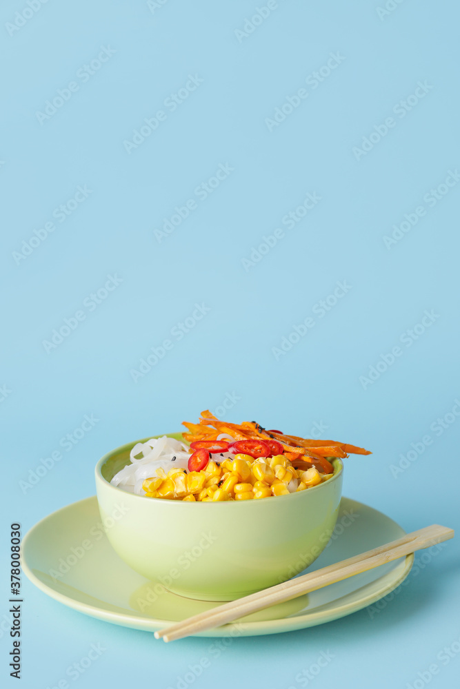 Bowl with tasty rice noodles and vegetables on color background