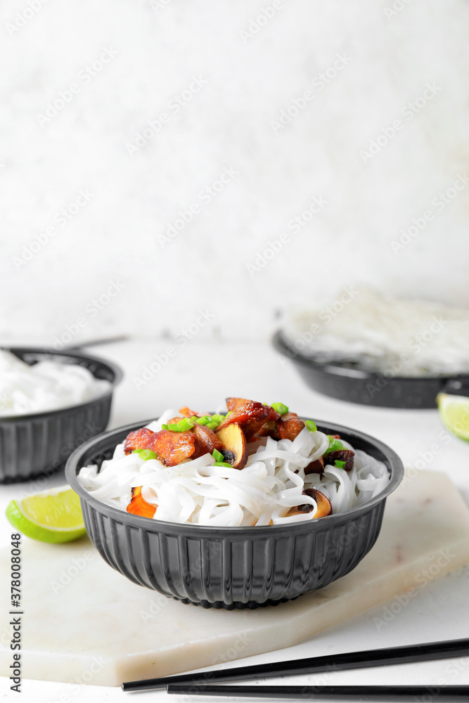 Bowl with tasty rice noodles and meat on white background