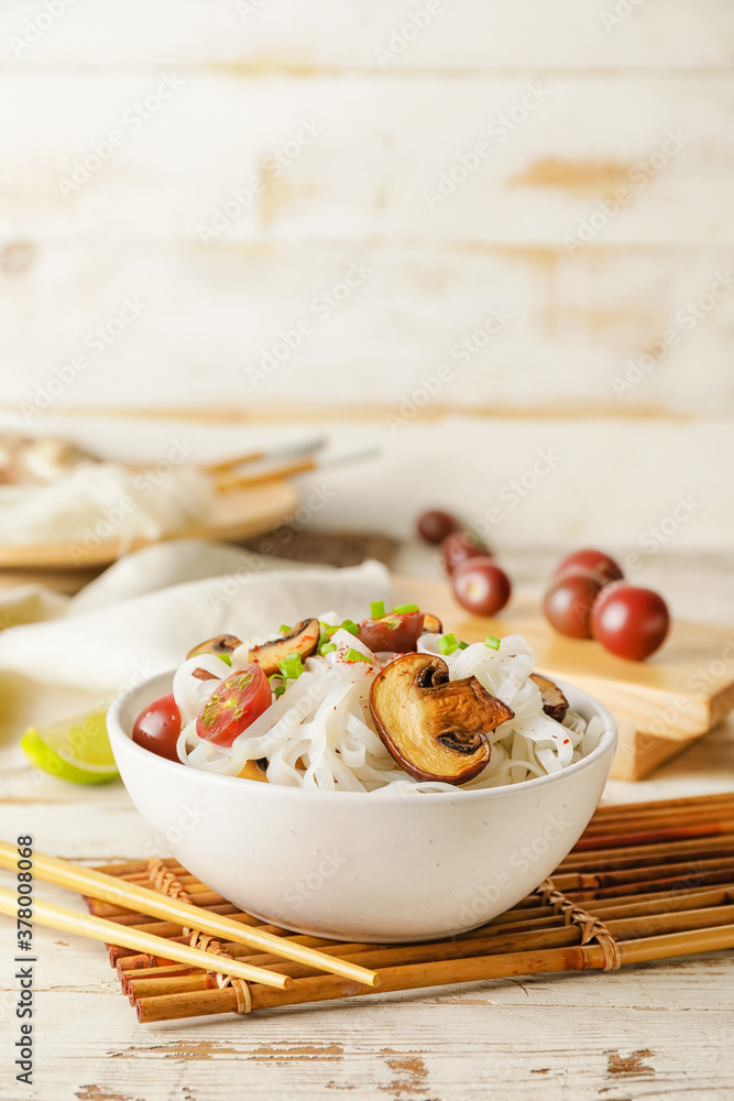 Bowl with tasty rice noodles and mushrooms on table